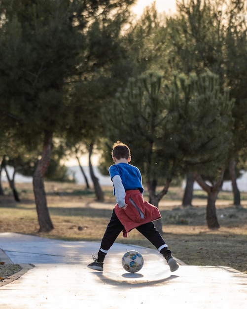 Achteraanzicht van jongen spelen met voetbal tussen de benen in de natuur Genieten van buitenshuis concept