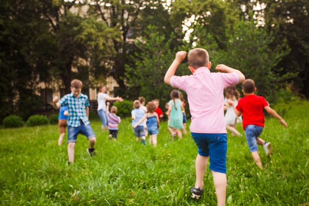 Achteraanzicht van kinderen die op groen gras in een park rennen