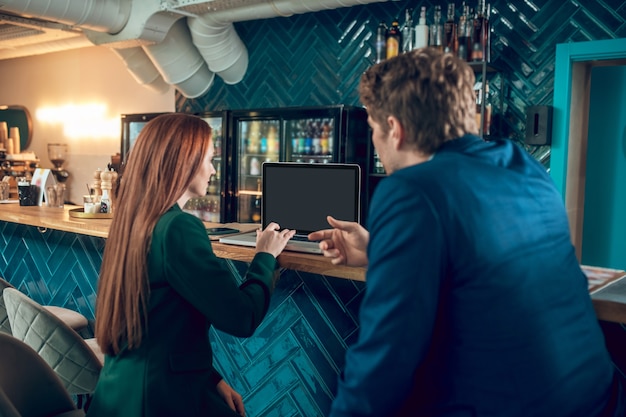 Achteraanzicht van man en vrouw zitten in de buurt van laptop