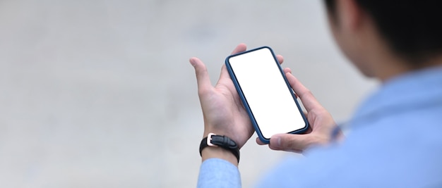Achteraanzicht van man handen met mobiele telefoon met leeg scherm voor uw tekstbericht of informatie-inhoud.