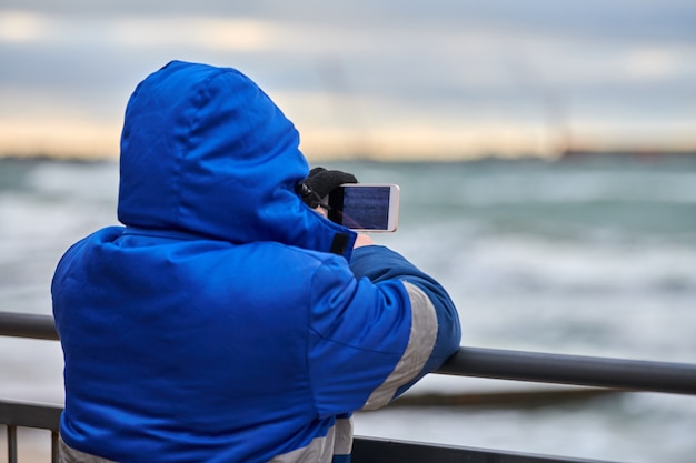 Achteraanzicht van man toerist die foto neemt van zeegezicht met smartphone