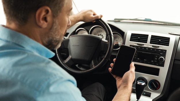 Achteraanzicht van mannelijke bestuurder met behulp van telefoon rijden auto panorama