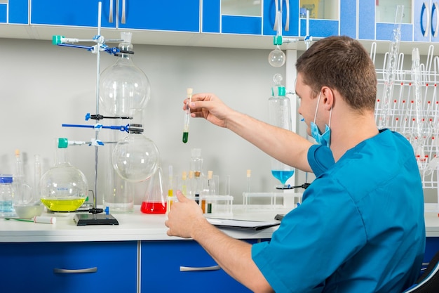 Achteraanzicht van mannelijke wetenschapper in uniform die wat onderzoek doet in een laboratorium. Gezondheidszorg en biotechnologie concept