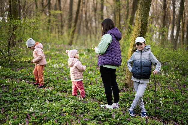 Achteraanzicht van moeder met drie kinderen die op bospad lopen Outdoor spring leisure concept