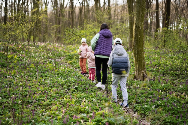 Achteraanzicht van moeder met drie kinderen die op bospad lopen outdoor spring leisure concept