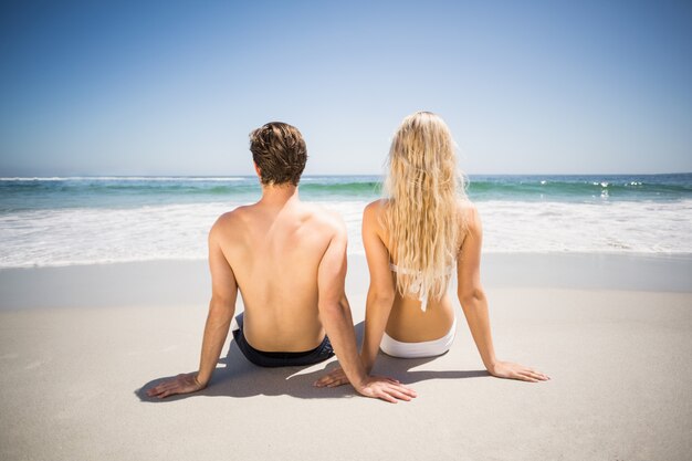 Achteraanzicht van paar zittend op het strand