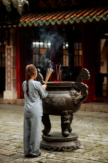 Foto achteraanzicht van religieuze vrouw met wierook branden in de tempel