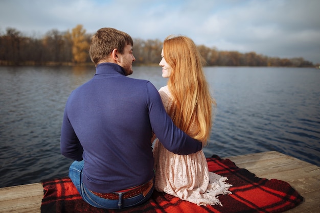 Achteraanzicht van romantische jonge paar zittend op de pier genieten van geweldig uitzicht