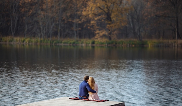 Achteraanzicht van romantische jonge paar zittend op de pier genieten van geweldig uitzicht