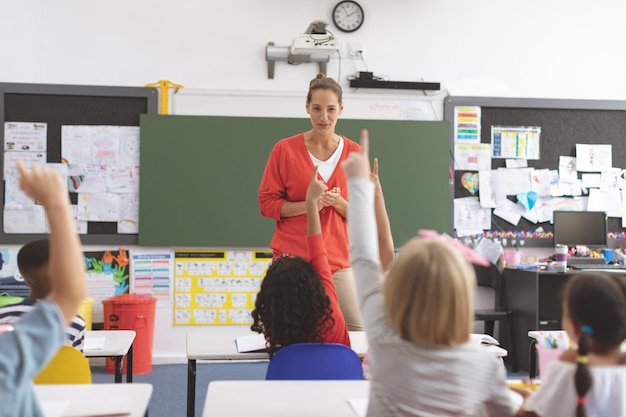 Achteraanzicht van schoolkinderen die hand opsteken om een vraag te beantwoorden