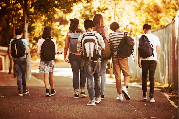 Achteraanzicht van schoolkinderen die op de weg op de campus op school lopen