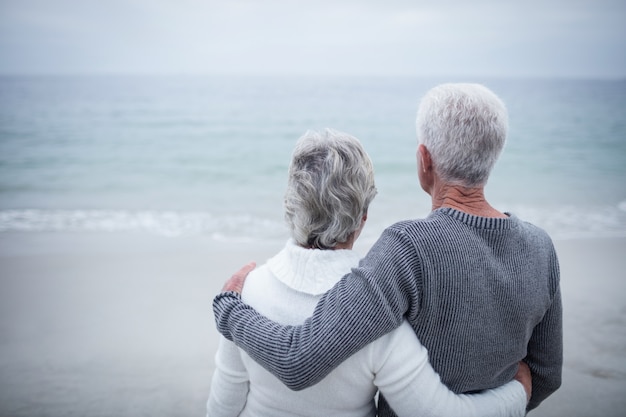 Achteraanzicht van senior paar omarmen op strand