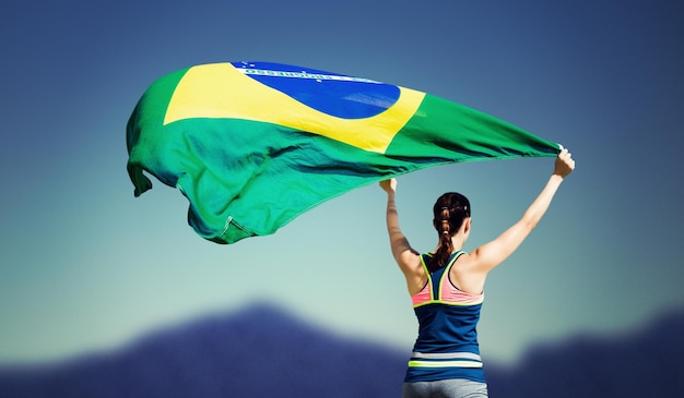 Achteraanzicht van sportvrouw die een Braziliaanse vlag opheft