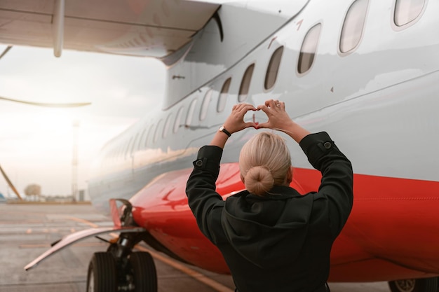 Achteraanzicht van stewardess die op vliegtuigen kijkt en tekenhart toont