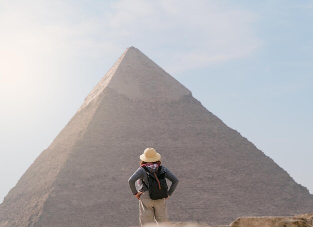 Achteraanzicht van toeristische vrouw die voor een piramide staat egypte cairo giza