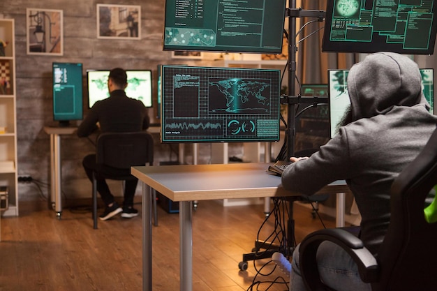 Achteraanzicht van twee hackers die samenwerken om chaos in de wereld te creëren met hun malware.