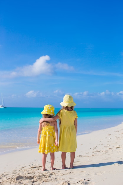 Achteraanzicht van twee kleine schattige meisjes kijken naar de zee op wit strand