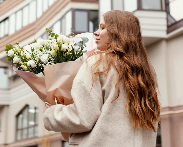 Achteraanzicht van vrouw met boeket bloemen buitenshuis