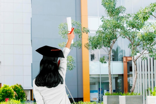 Achteraanzicht van vrouw tilt diploma op universiteitswerf