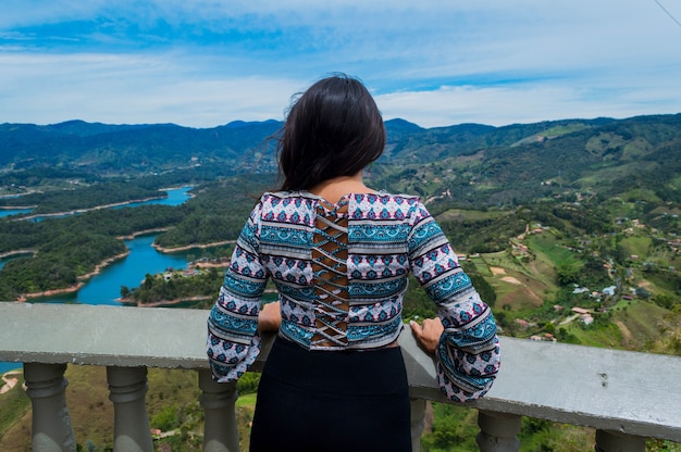 Achteraanzicht van vrouwelijke toerist die de natuur in Guatape Colombia overweegt vanaf de top van Penol-steen