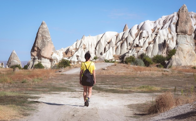 Achteraanzicht van vrouwelijke toerist die naar grotwoningen in Cappadocië, Turkije loopt