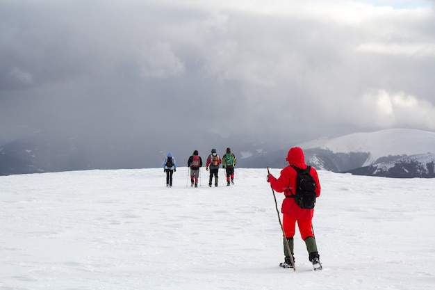 Achteraanzicht van wandelaars lopen op besneeuwde heuvel in de bergen van de winter.