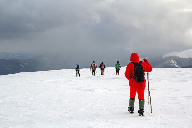 Achteraanzicht van wandelaars lopen op besneeuwde heuvel in de bergen van de winter.