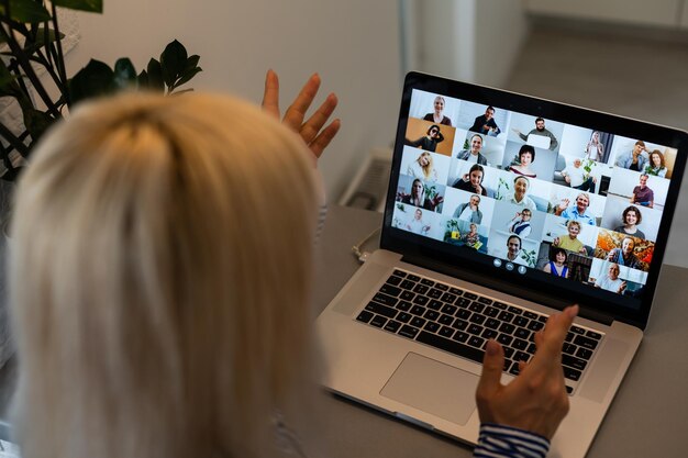 Achteraanzicht van zakenvrouw die met haar collega's praat over plan in videoconferentie. multi-etnisch business team dat laptop gebruikt voor een online vergadering in videogesprek. groep mensen slim thuiswerken