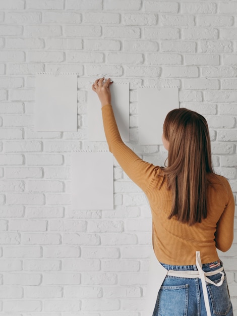 Foto achteraanzicht vrouw papier op muur te zetten