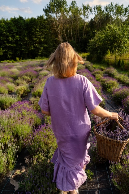 Foto achteraanzicht vrouw wandelen met lavendelmand