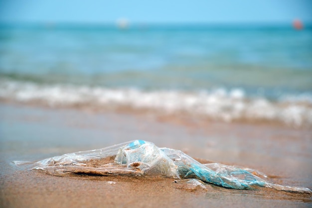 Achtergelaten plastic zak afval op zandstrand Leeg gebruikt vuil afval op zee Milieuvervuiling Ecologisch probleem