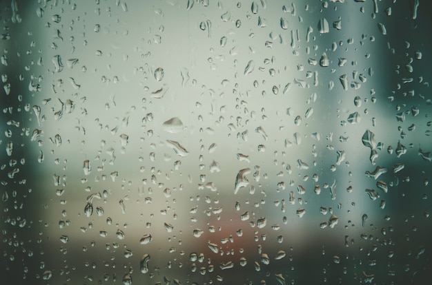Achtergrond en behang door regenachtige daling en waterdalingen op vensterglas.