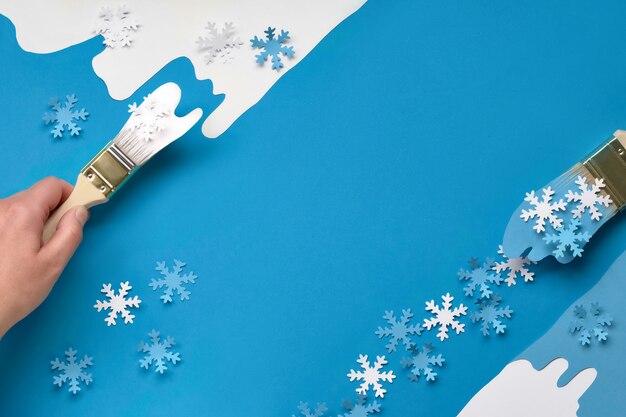 Achtergrond in blauw en wit met borstels geladen met papier sneeuwvlokken, kopie-ruimte