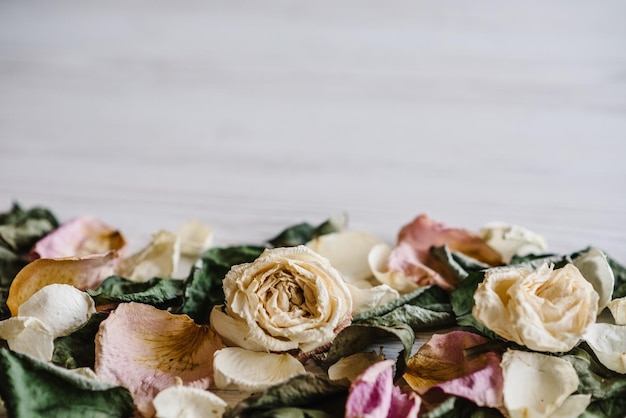 Achtergrond met droge rozenblaadjes bloemen en bladeren bloemen samenstelling frame gemaakt van gedroogde roos op witte houten achtergrond plaats voor tekst en design