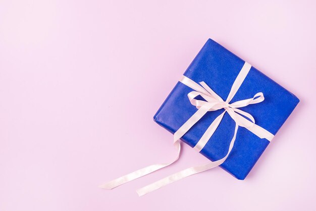 Achtergrond met geschenkdozen in blauw inpakpapier met linten op een roze achtergrond