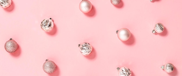 Achtergrond met mooie glanzende roze decoratieve ballen op een roze achtergrond. Bovenaanzicht, plat gelegd. Banier.