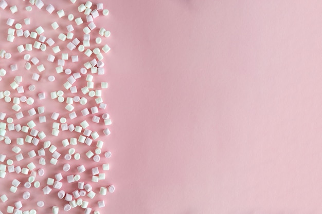 Achtergrond of textuur van roze en witte mini marshmallows op roze achtergrond met vrije ruimte voor tekst