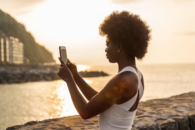 Achtergrond van een Afrikaanse vrouw die een foto maakt van de zonsondergang in de oceaan