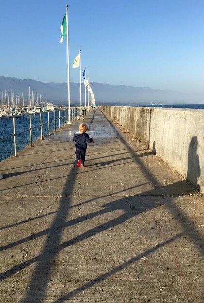 Achtergrond van een baby jongen die op het voetpad loopt tegen een heldere blauwe hemel