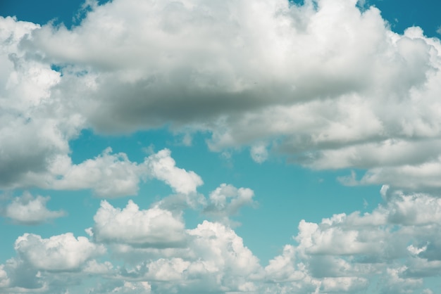 Achtergrond van een blauwe lucht met grote witte wolken. Zomer sfeervolle achtergrond. Warme verzadigde kleuren