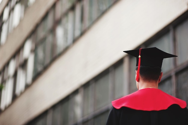 Foto achtergrond van een man die een graduatiejurk draagt tegen het gebouw