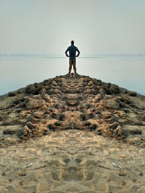 Foto achtergrond van een man die op het strand staat tegen een heldere hemel