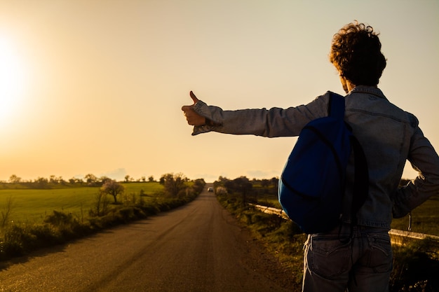 Foto achtergrond van een man die tijdens de zonsondergang op het veld tegen de hemel staat