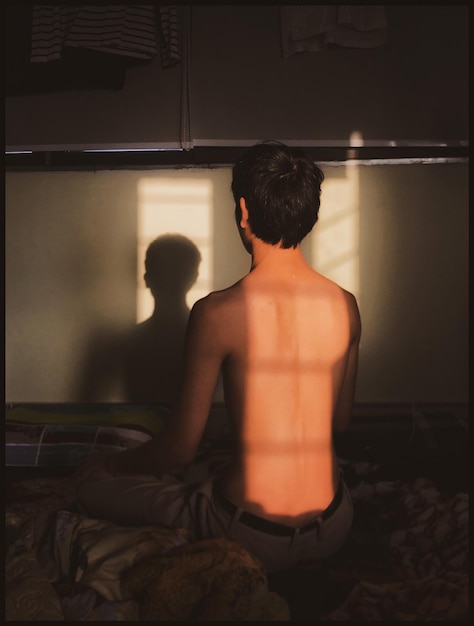 Foto achtergrond van een shirtloze man die thuis op bed zit