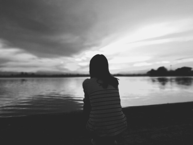 Foto achtergrond van een vrouw die aan het meer zit tegen de lucht