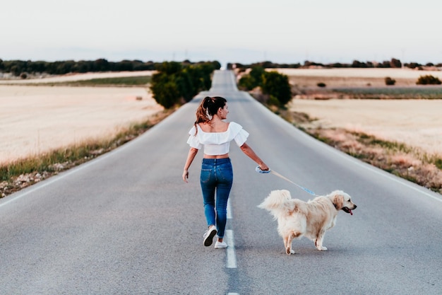 Achtergrond van een vrouw die met een hond op de weg loopt