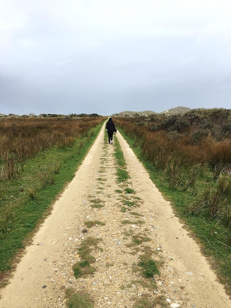 Foto achtergrond van een vrouw die op de weg loopt te midden van het landschap tegen de lucht