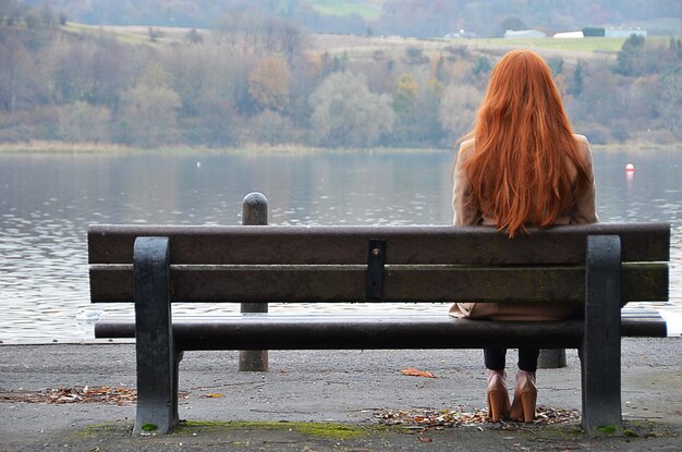 Achtergrond van een vrouw die op een bankje tegen het meer zit
