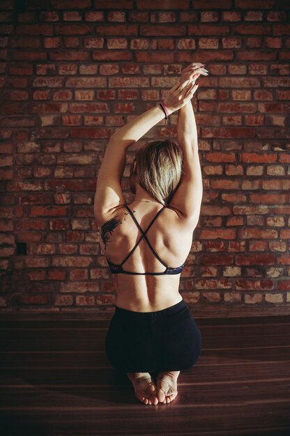 Foto achtergrond van een vrouw die zich tegen een bakstenen muur uitstrekt