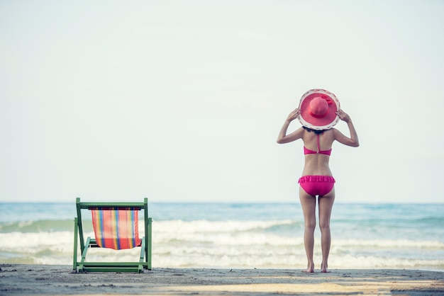 Achtergrond van een vrouw in bikini die op het strand staat tegen een heldere hemel
